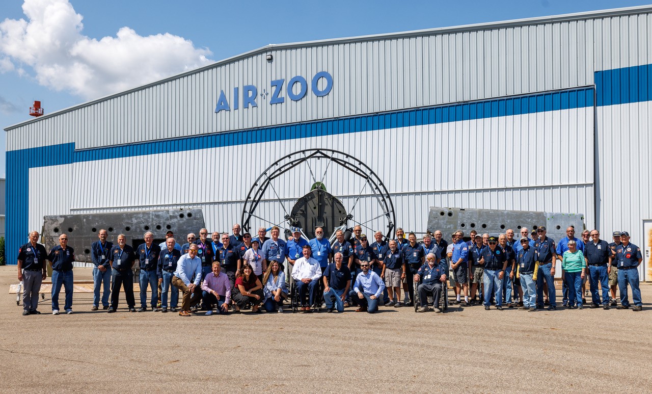large group of people posed together in front of the Air Zoo museum