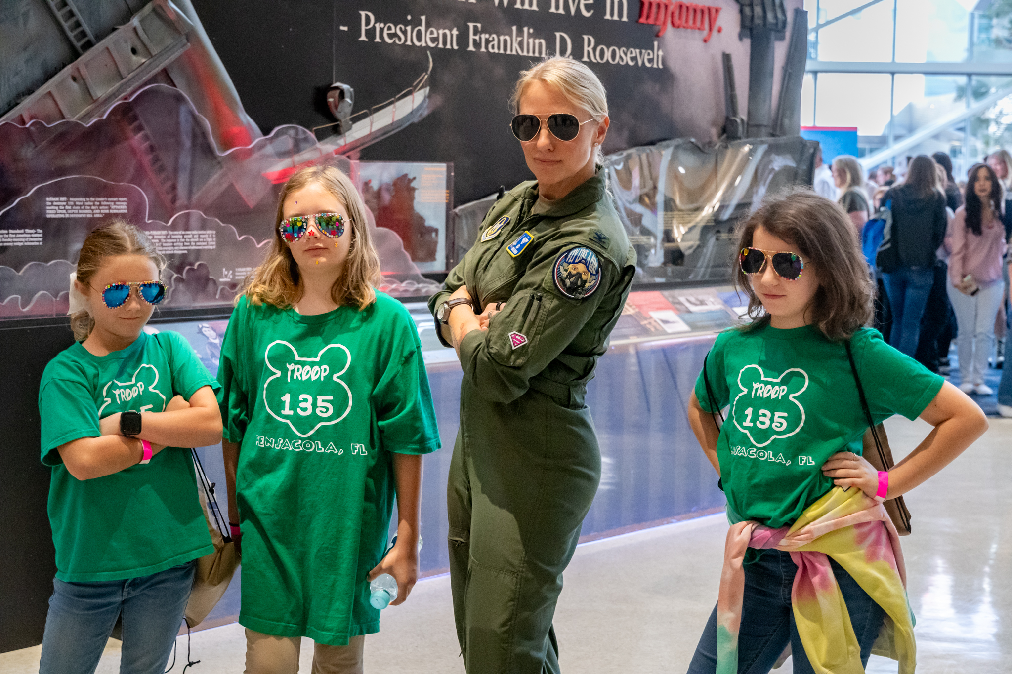 Colonel Vanessa Siren Mahan posing with her arms crossed with 3 girls in green tshirts
